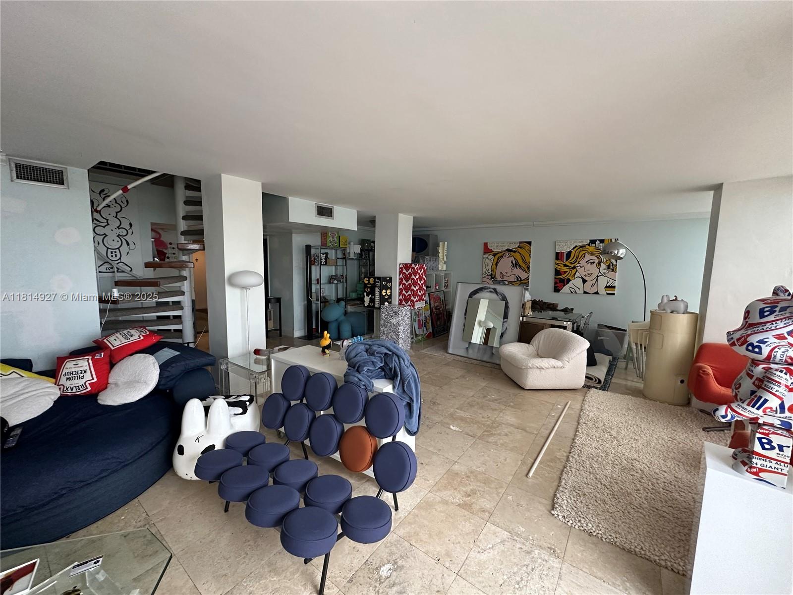 A living room features a spiral staircase, tile flooring, pop art, and eclectic furniture — 600 NE 36th St, Miami FL 33137, MIAMI, FL