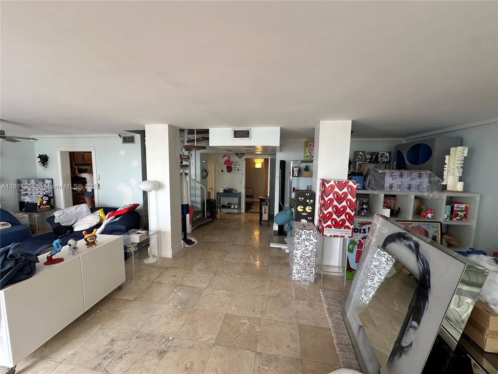 A living area features tile flooring, a spiral staircase, and various decorative art pieces — 600 NE 36th St, Miami FL 33137, MIAMI, FL