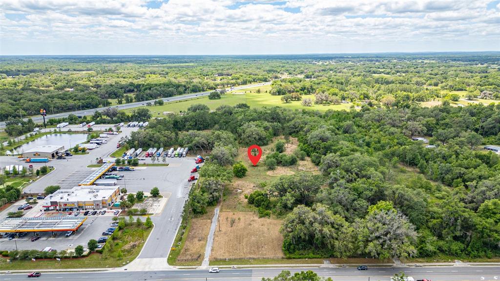 An aerial view shows a vacant lot marked with a pin next to a gas station — 2623 W C 48, BUSHNELL, FL