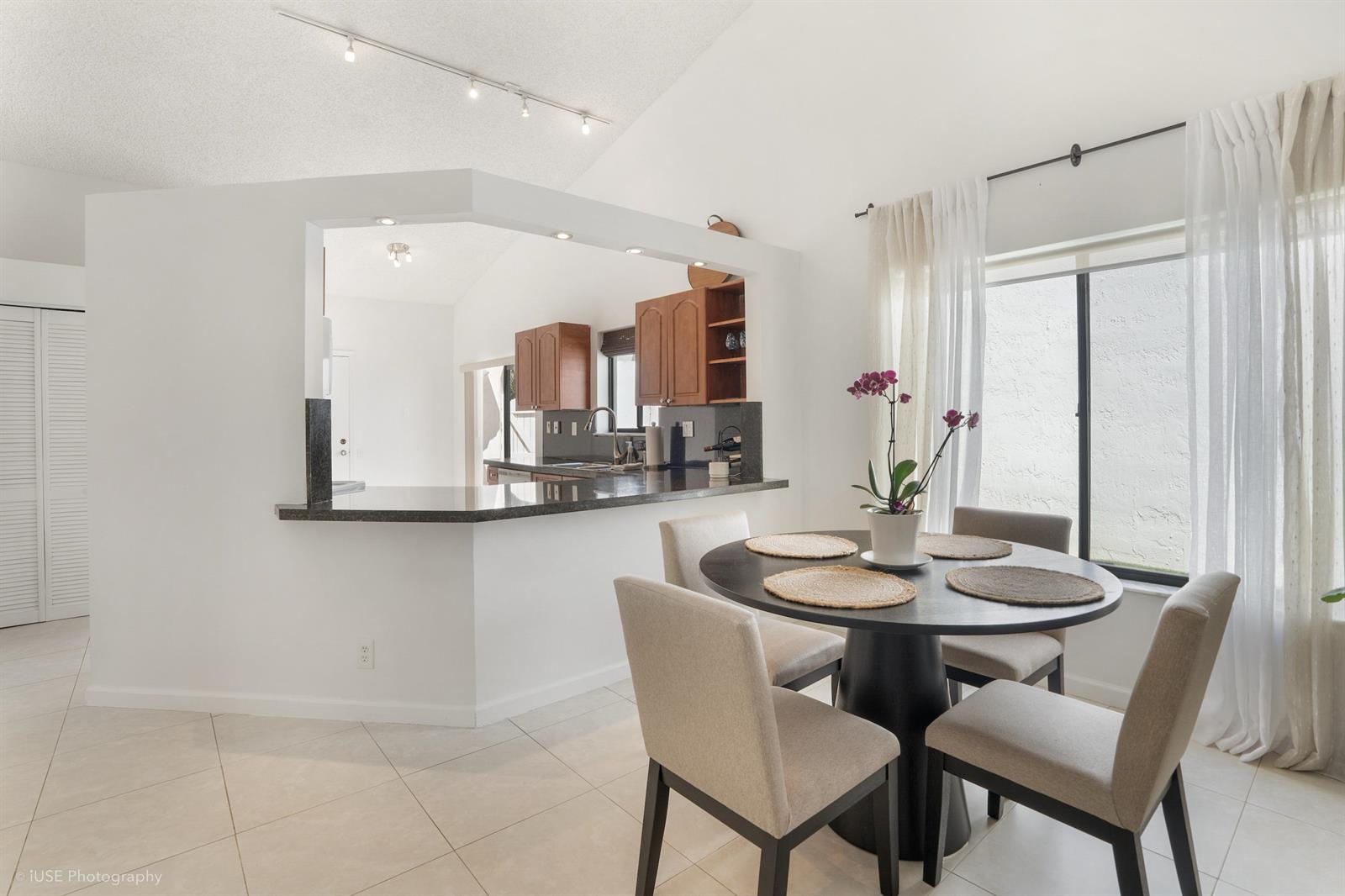 A dining area with a round table and chairs sits adjacent to a kitchen pass-through — 21712 Wapford Way, Boca Raton FL 33486, BOCA RATON, FL