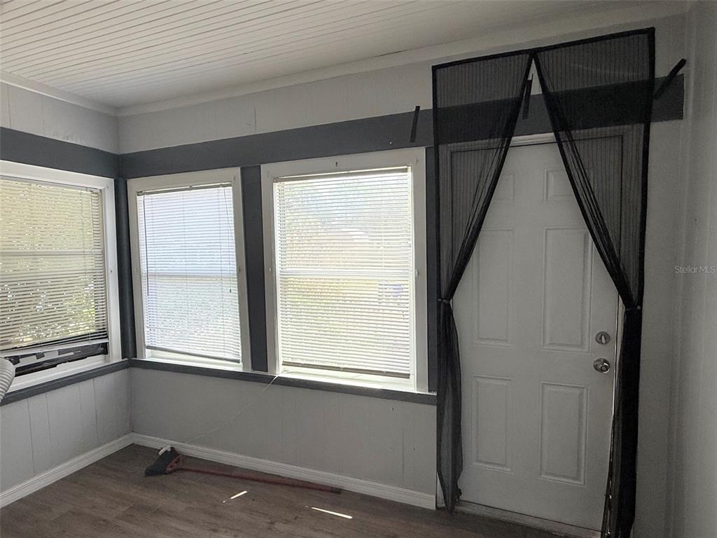A sunroom features gray walls, wood-look flooring, two windows with blinds, and a door with a screen — 1933 47TH STREET S, ST PETERSBURG, FL