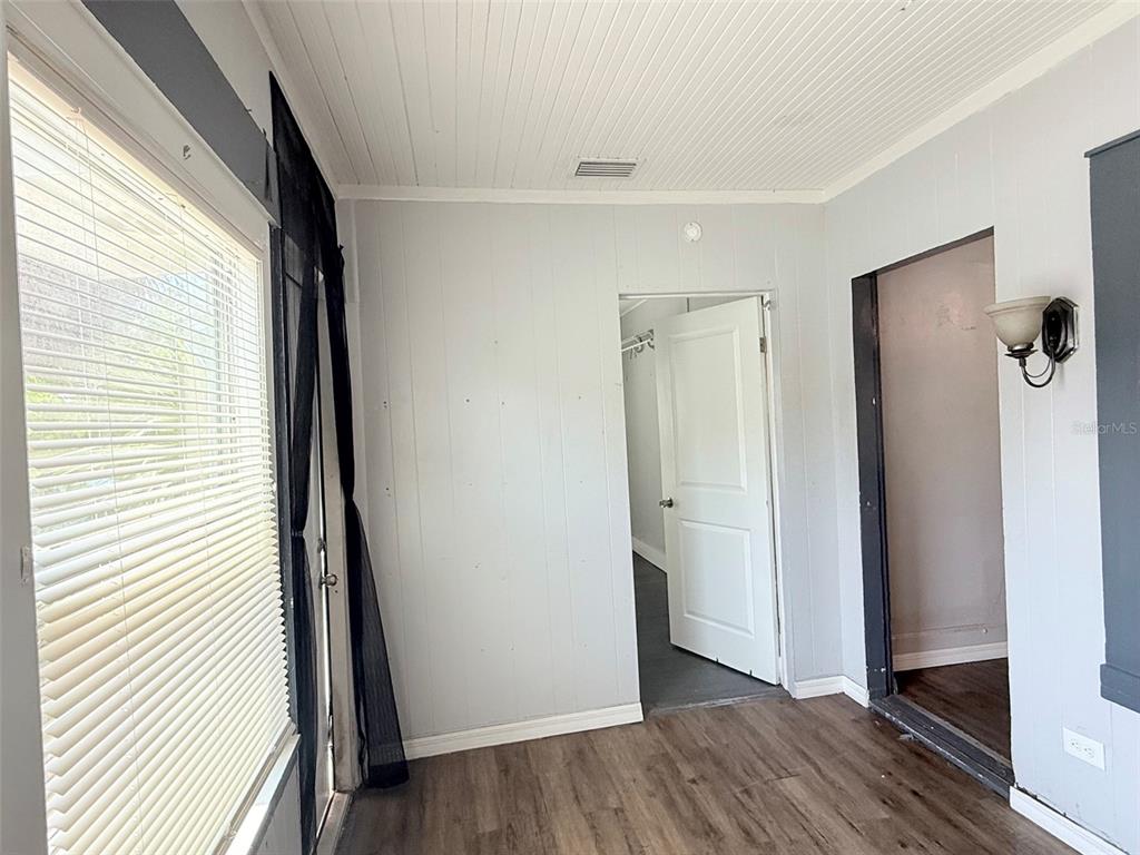 A room with light gray paneled walls, wood-look flooring, and two open doorways — 1933 47TH STREET S, ST PETERSBURG, FL