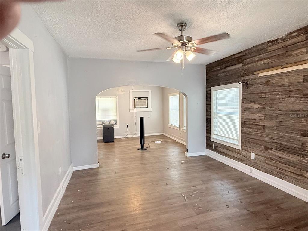 A living room features wood-look flooring, a wood-plank accent wall, and an arched entryway — 1933 47TH STREET S, ST PETERSBURG, FL