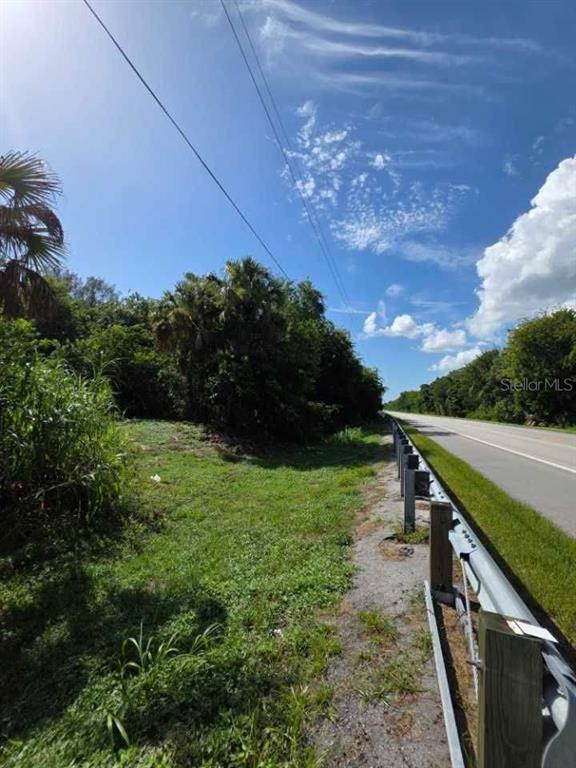 A grassy, wooded lot sits adjacent to a paved road with a metal guardrail — 16980 SW CONNERS HIGHWAY, CANAL POINT, FL