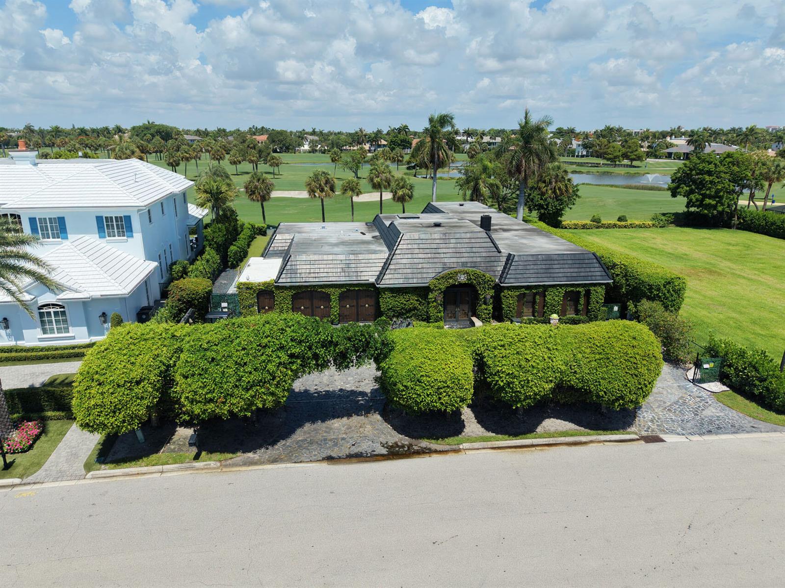 An aerial view shows a single-story house with ivy-covered walls and a dark shingled roof — 1877 Royal Palm Way, Boca Raton FL 33432, BOCA RATON, FL