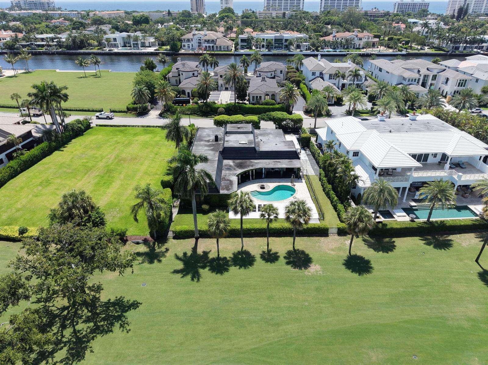 An aerial view shows a house with a dark roof and pool next to a golf course — 1877 Royal Palm Way, Boca Raton FL 33432, BOCA RATON, FL