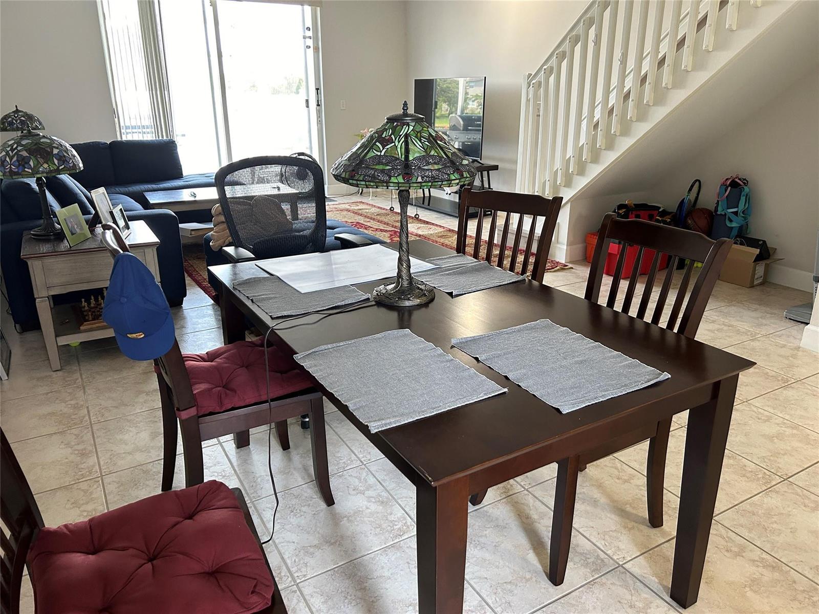 A dining area with a dark wood table, chairs with red cushions, and a stained-glass lamp — 3730 San Simeon Circle, Weston FL 33331, WESTON, FL