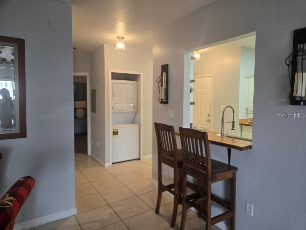 A kitchen pass-through window with a breakfast bar overlooks a tiled hallway with laundry appliances — 13226 GALICIA STREET UNIT 204, ORLANDO, FL