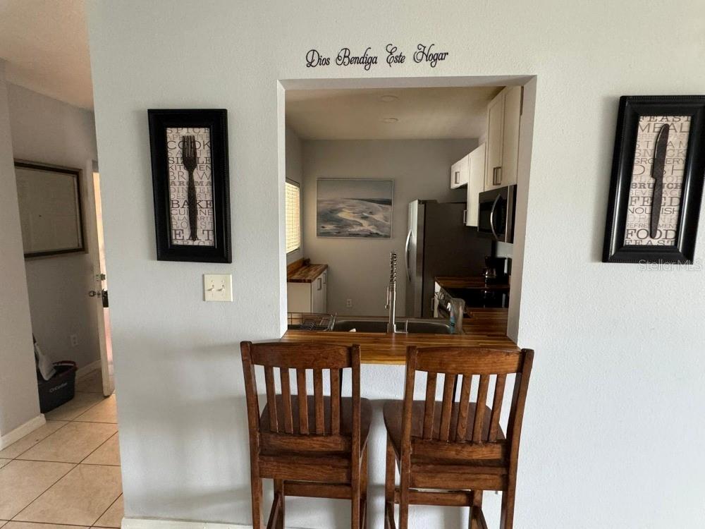 A kitchen pass-through window features a wooden breakfast bar with two chairs and wall art — 13226 GALICIA STREET UNIT 204, ORLANDO, FL