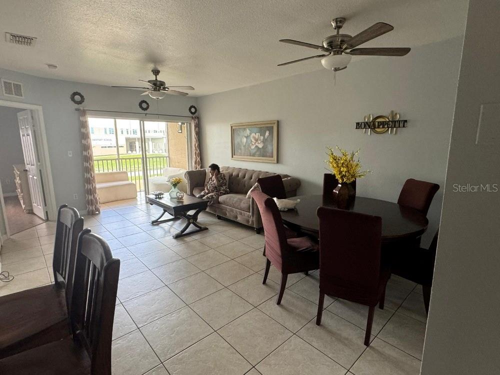 A living and dining room area features tile flooring, ceiling fans, and a sliding glass door — 13226 GALICIA STREET UNIT 204, ORLANDO, FL