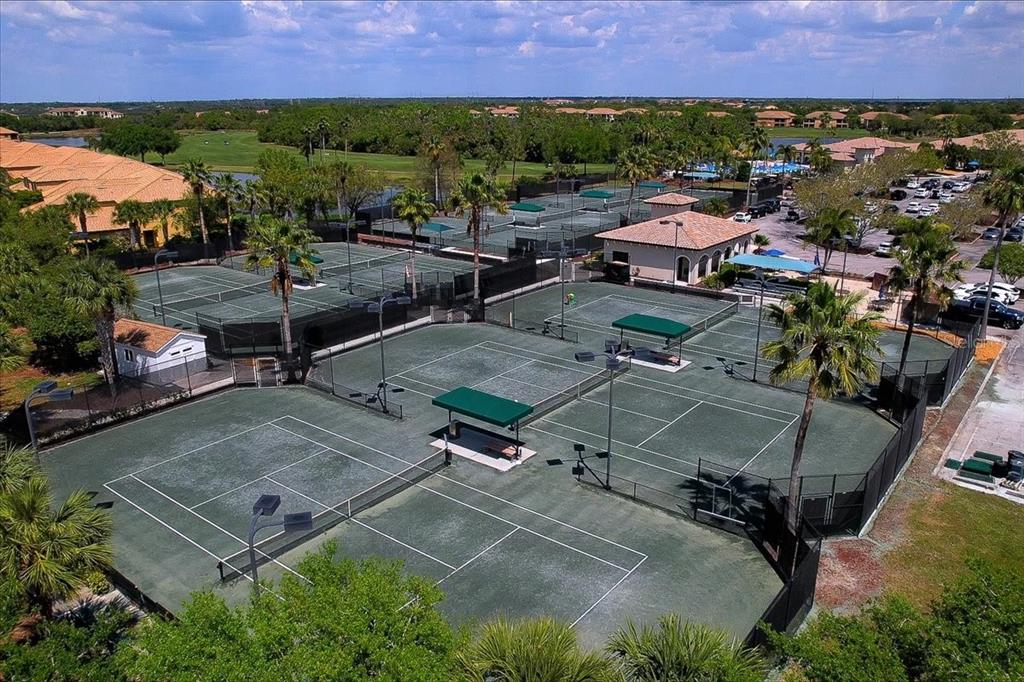 An aerial view of multiple outdoor tennis courts surrounded by palm trees and a clubhouse — 7607 GRAND ESTUARY TRAIL UNIT 101, BRADENTON, FL