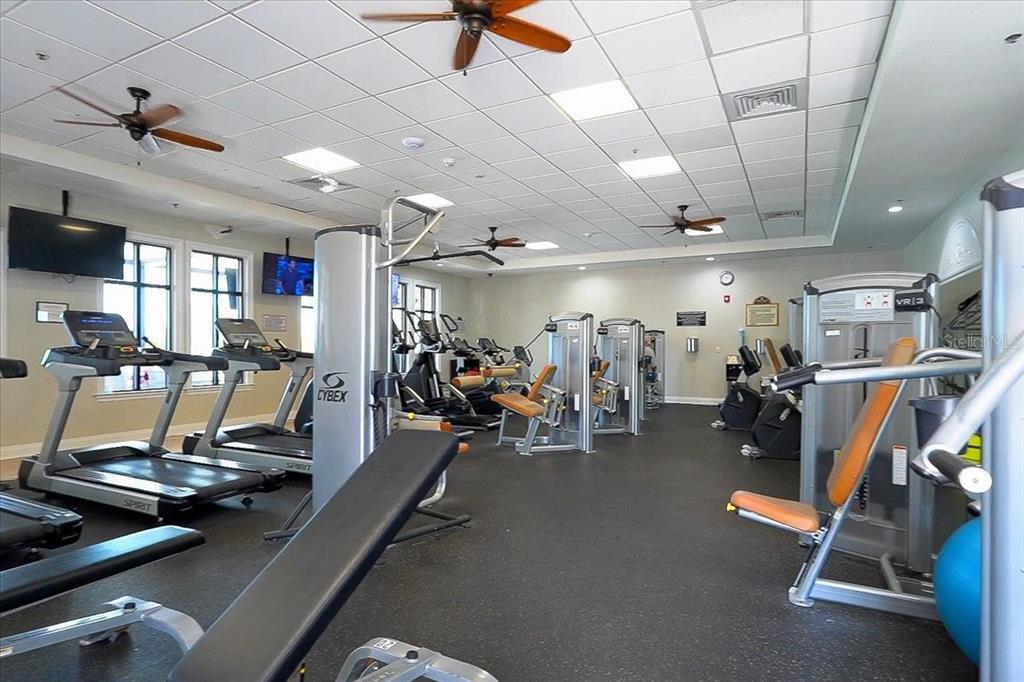 A fitness center features multiple treadmills, weight machines, ceiling fans, and a black rubber floor — 7607 GRAND ESTUARY TRAIL UNIT 101, BRADENTON, FL