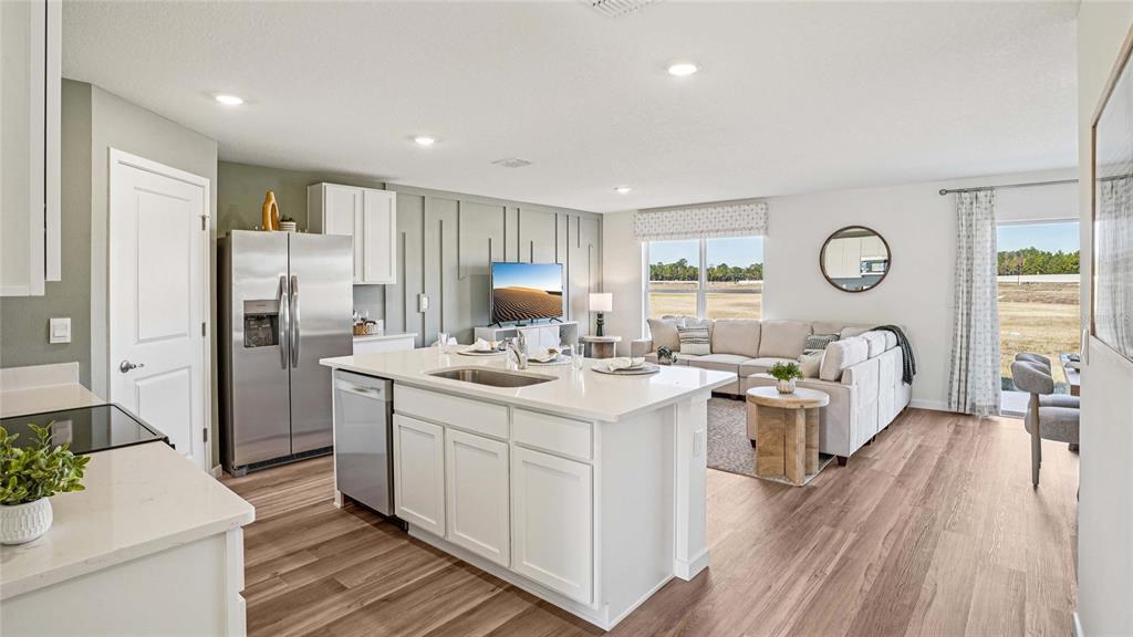 A kitchen with a white island and stainless steel appliances opens to a living area — 2058 NE 28TH PLACE, OCALA, FL