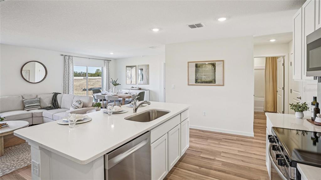 A kitchen island with a stainless steel sink overlooks an open-concept living and dining area — 2058 NE 28TH PLACE, OCALA, FL