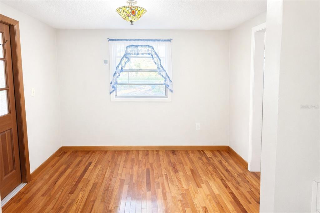 A room with hardwood floors, a window with a valance, and a stained-glass light fixture — 10019 CURLEY ROAD, SAN ANTONIO, FL
