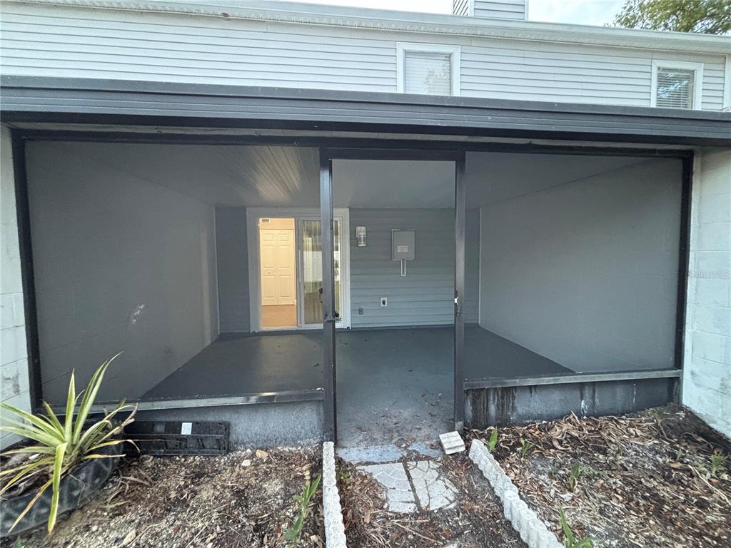 A covered patio with gray painted floors and walls features a central screen door entrance — 11804 CYPRESS HILL CIRCLE UNIT 45, TAMPA, FL