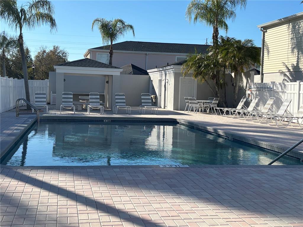 A rectangular swimming pool is surrounded by a paved deck, lounge chairs, and a gazebo — 11804 CYPRESS HILL CIRCLE UNIT 45, TAMPA, FL