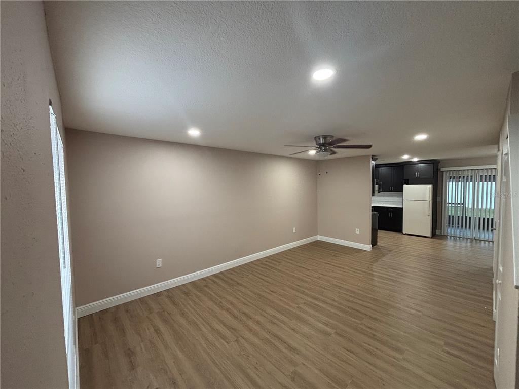 An open-concept living area with light wood-look flooring, recessed lighting, and an adjacent kitchen — 11804 CYPRESS HILL CIRCLE UNIT 45, TAMPA, FL