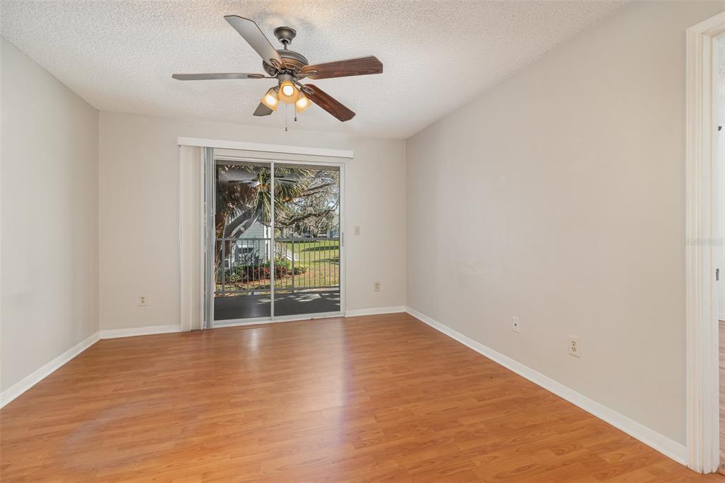 An empty room with wood-look flooring, a ceiling fan, and a sliding glass door — 717 SECRET HARBOR LANE UNIT 203, LAKE MARY, FL