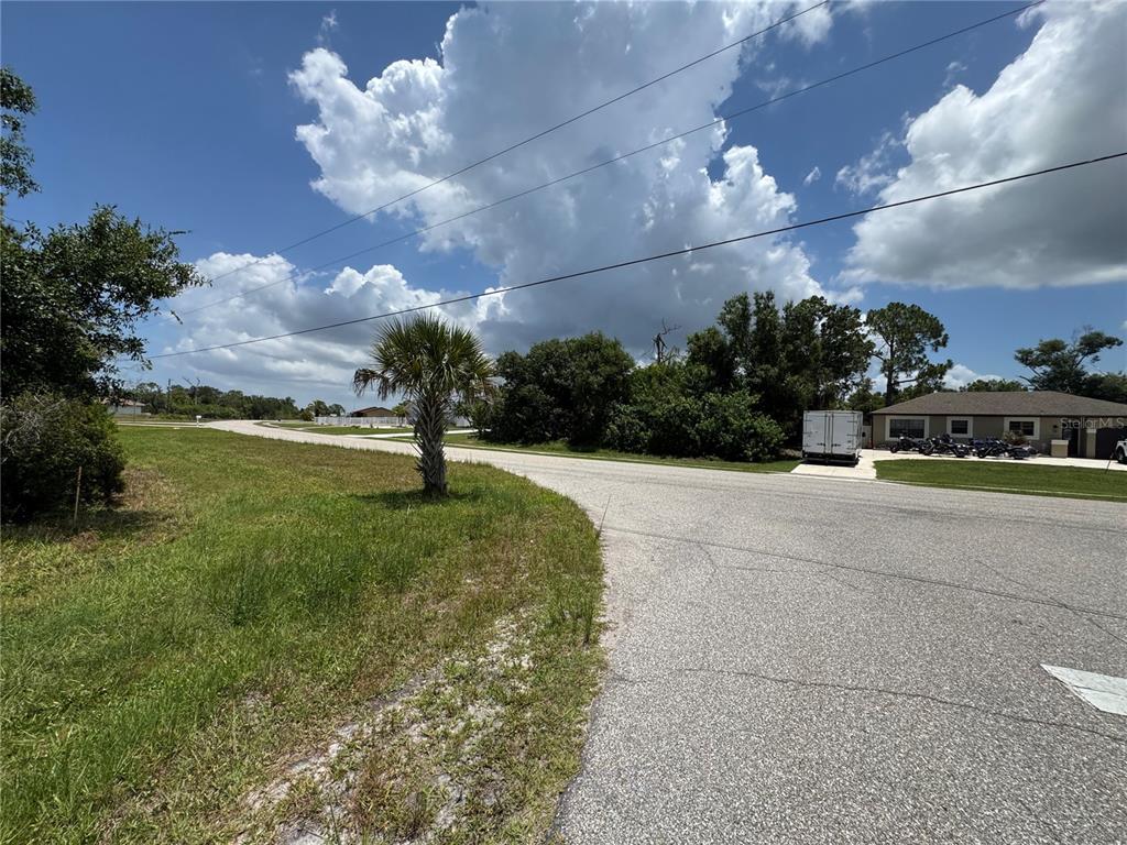 A paved road curves past a grassy lot with a palm tree under a cloudy sky — 9798 GULFSTREAM BOULEVARD, ENGLEWOOD, FL