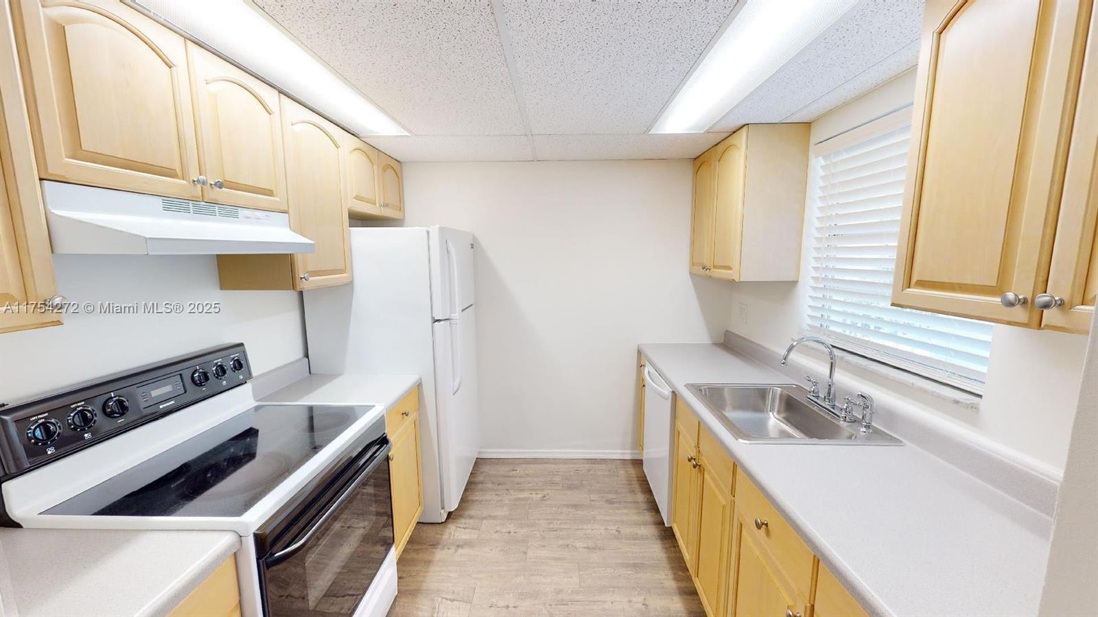 This galley kitchen features light wood cabinets, white appliances, and a stainless steel sink — 300 Ocean Drive # 22, Key Largo FL 33037, KEY LARGO, FL