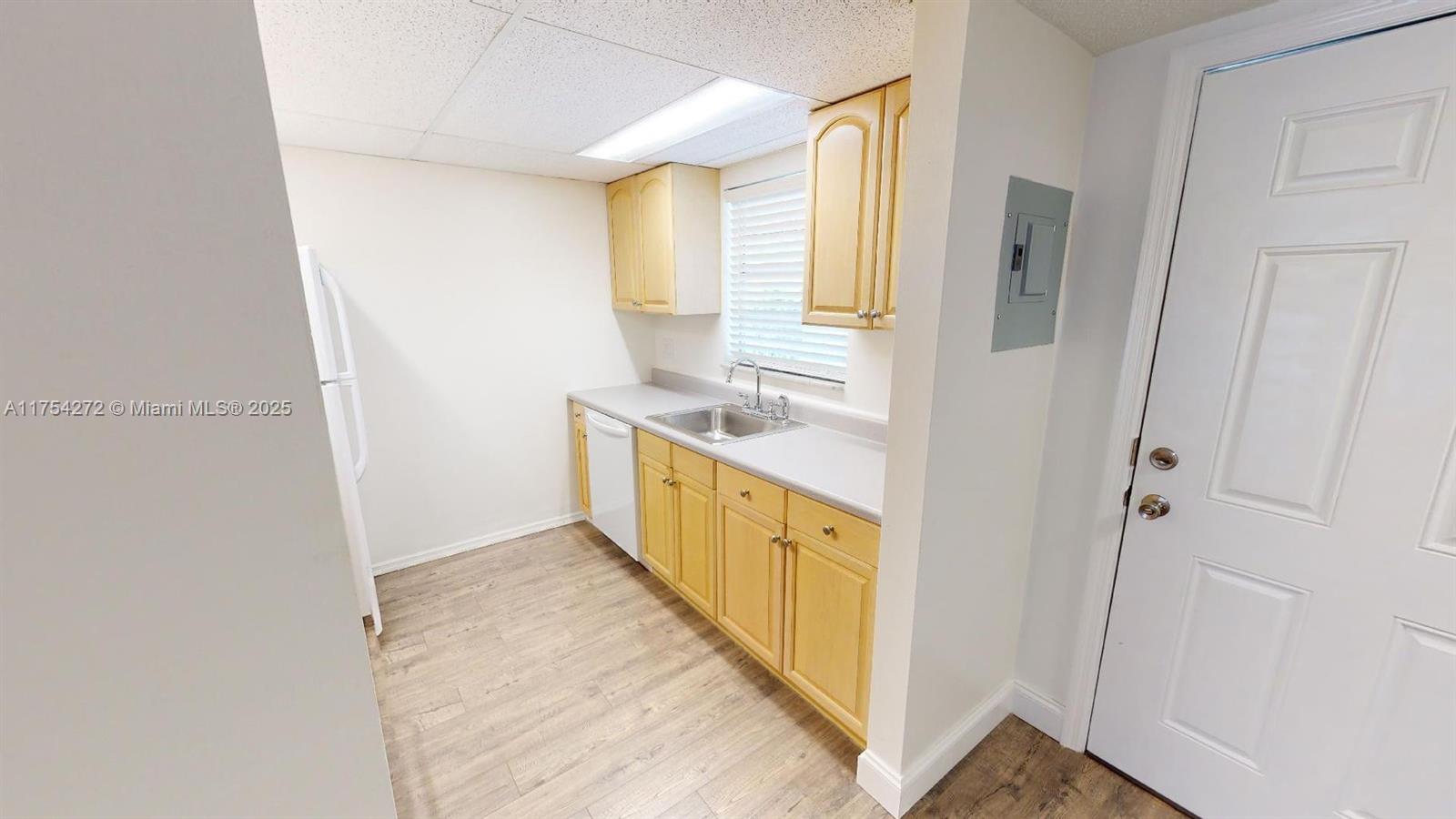 A small kitchen features light wood cabinets, a stainless steel sink, and light-colored flooring — 300 Ocean Drive # 22, Key Largo FL 33037, KEY LARGO, FL