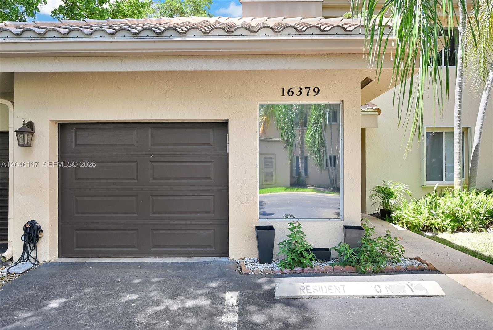 The exterior of a residential building features a brown garage door, a reflective window, and a parking space — 16379 Malibu Dr # 50, Weston FL 33326, WESTON, FL