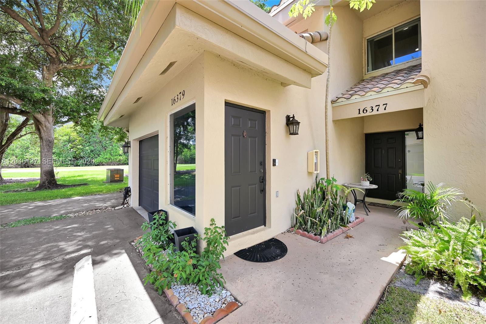 The exterior view shows two adjacent residential entrances with dark doors and tan stucco walls — 16379 Malibu Dr # 50, Weston FL 33326, WESTON, FL