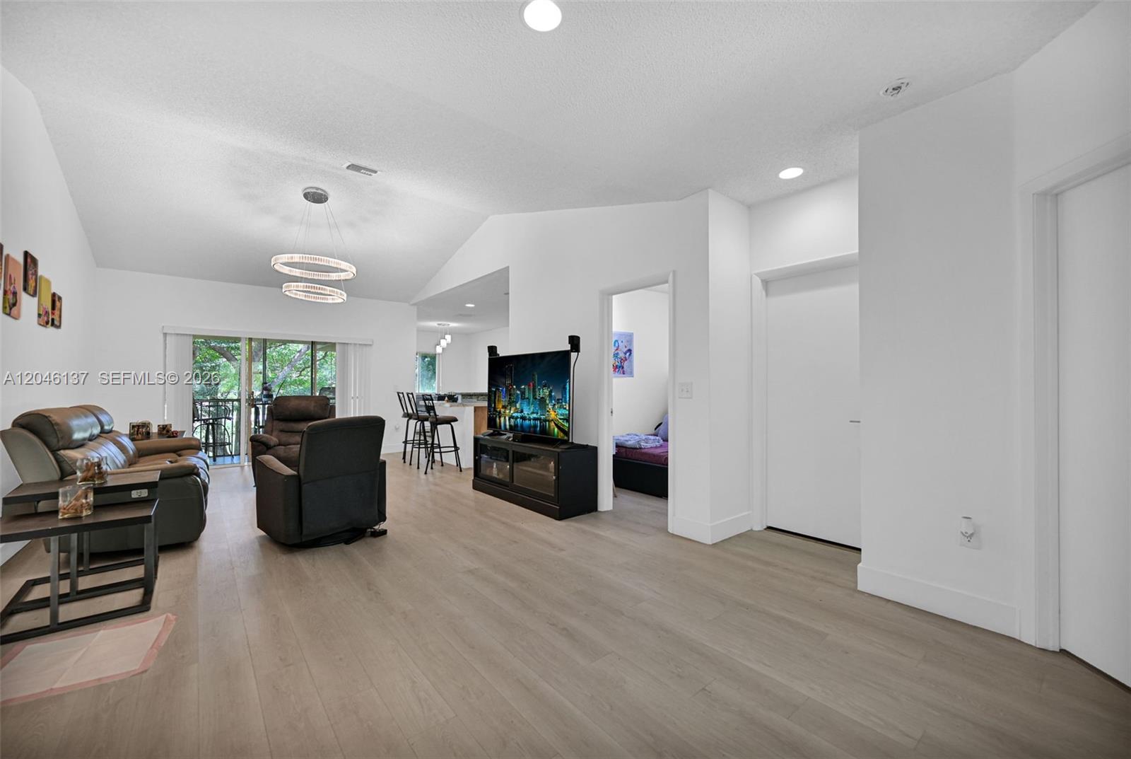 A living room features light wood flooring, a vaulted ceiling, and an open kitchen view — 16379 Malibu Dr # 50, Weston FL 33326, WESTON, FL