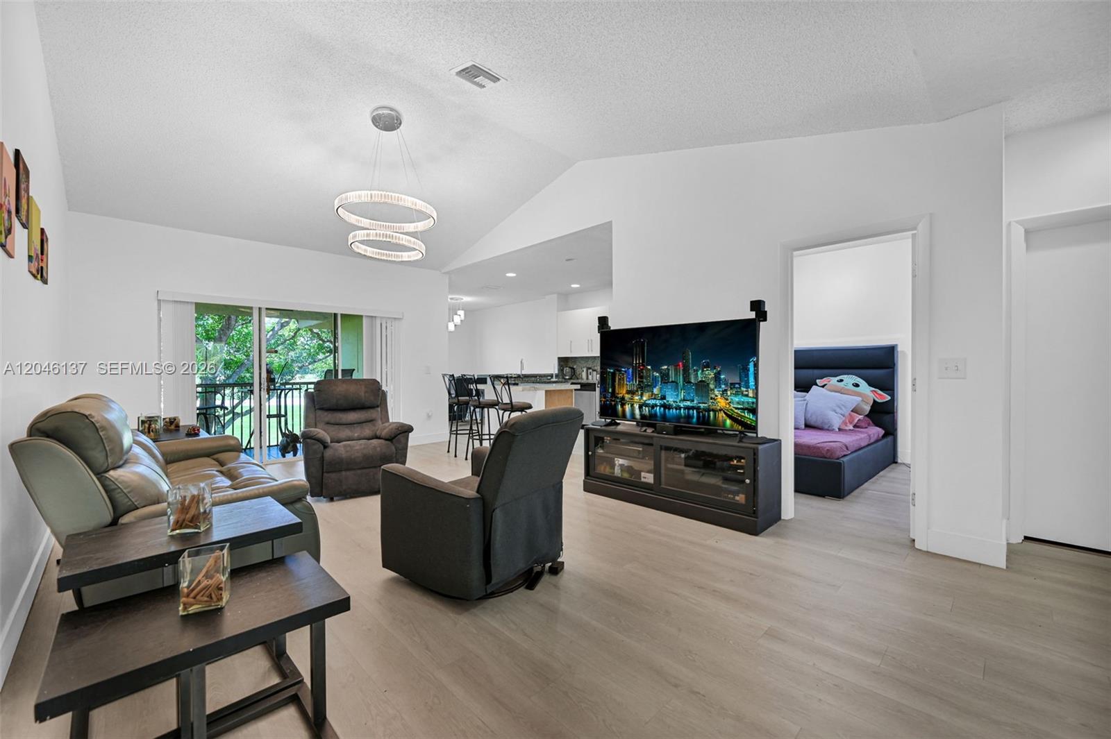 A living room features light wood flooring, a vaulted ceiling, and a view of greenery — 16379 Malibu Dr # 50, Weston FL 33326, WESTON, FL