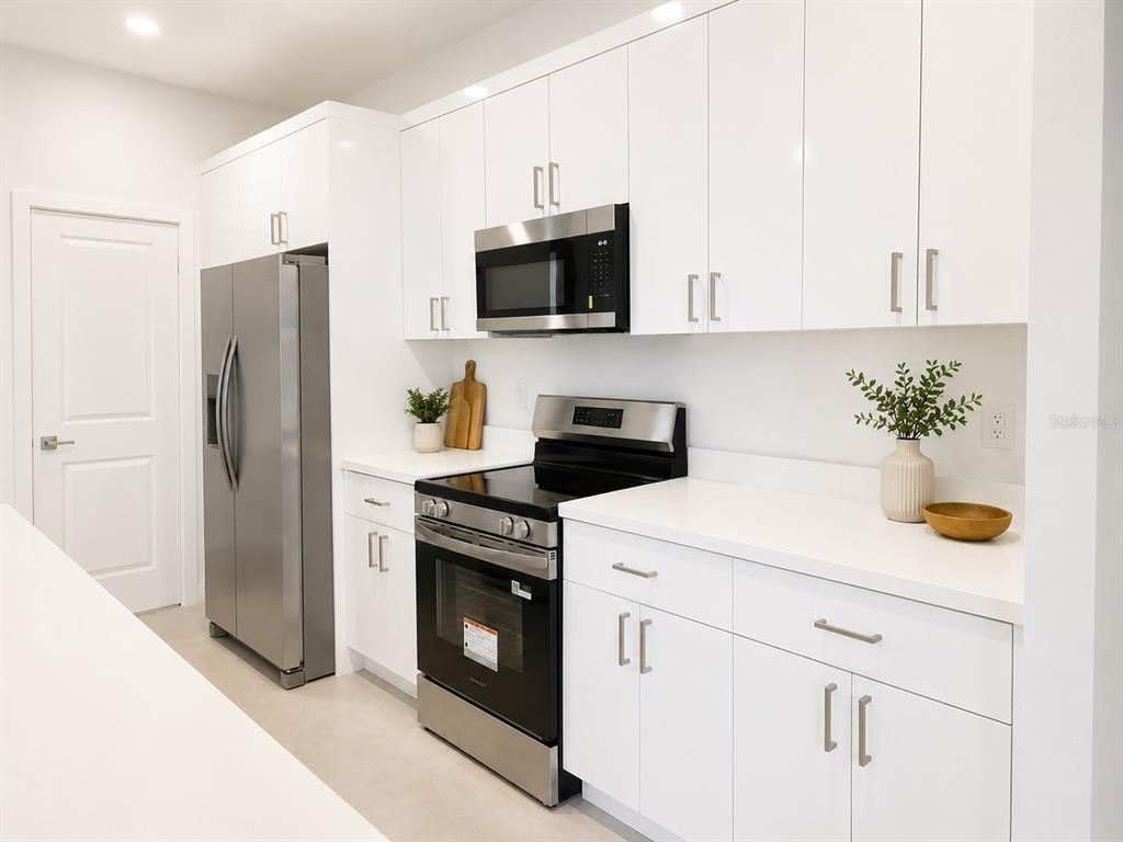 A modern kitchen features white cabinets, stainless steel appliances, and white countertops — 503 10 STREET W, LEHIGH ACRES, FL