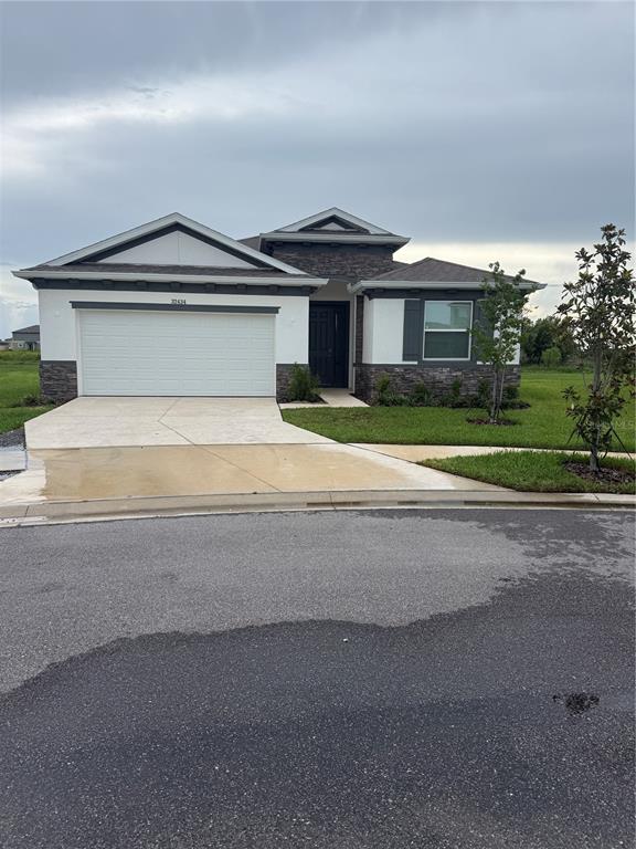 A single-story house with a white exterior, stone accents, and a two-car garage — 32434 OSPREY PEAK WAY, SAN ANTONIO, FL