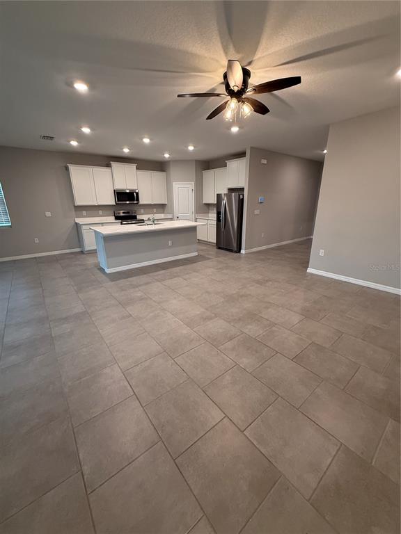 A kitchen with white cabinets, stainless steel appliances, a center island, and tiled flooring — 32434 OSPREY PEAK WAY, SAN ANTONIO, FL