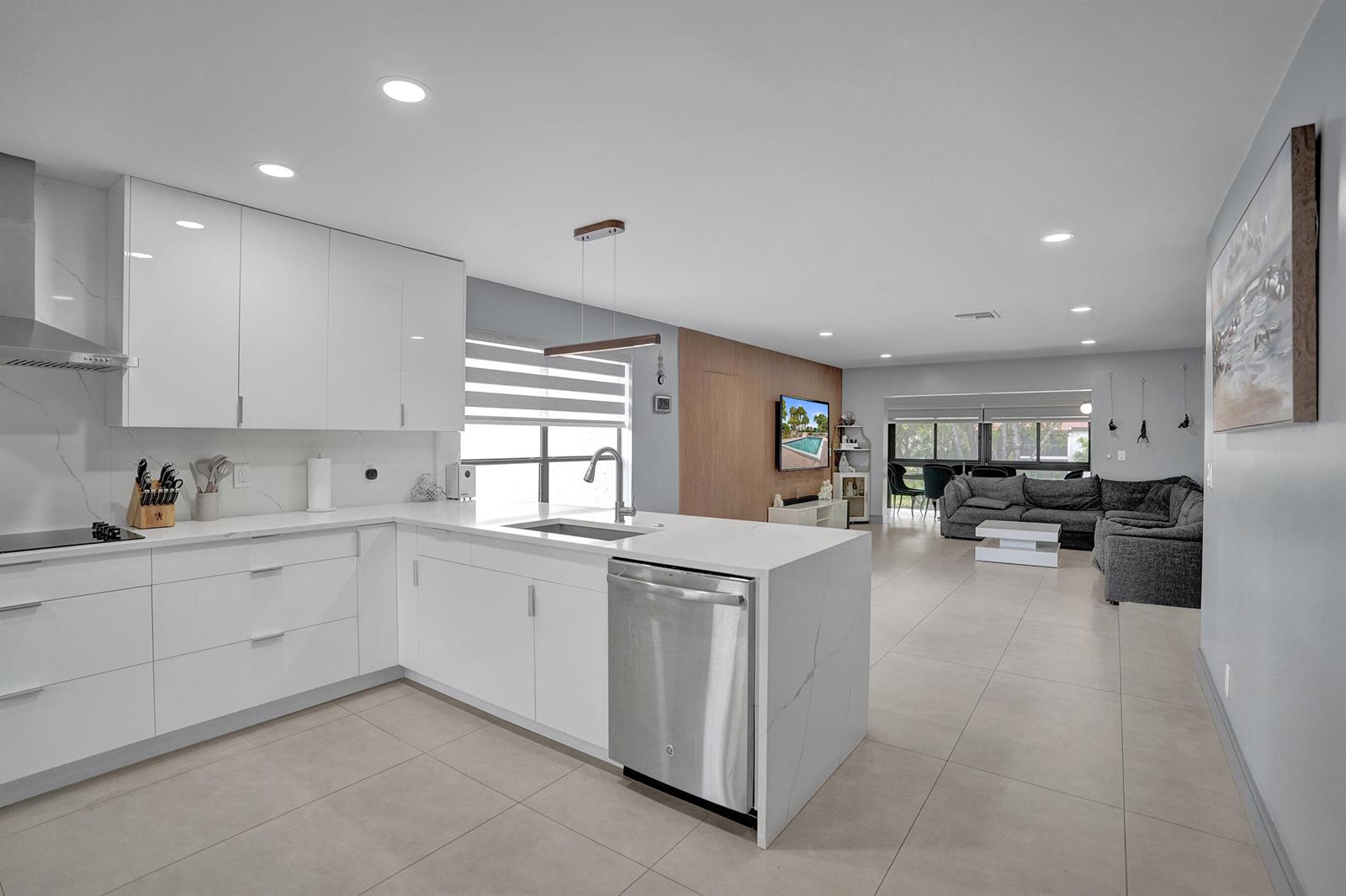 A modern kitchen with white cabinets and quartz countertops opens into a spacious living area — 21675 Tall Palm Circle # 2b, Boca Raton FL 33433, BOCA RATON, FL