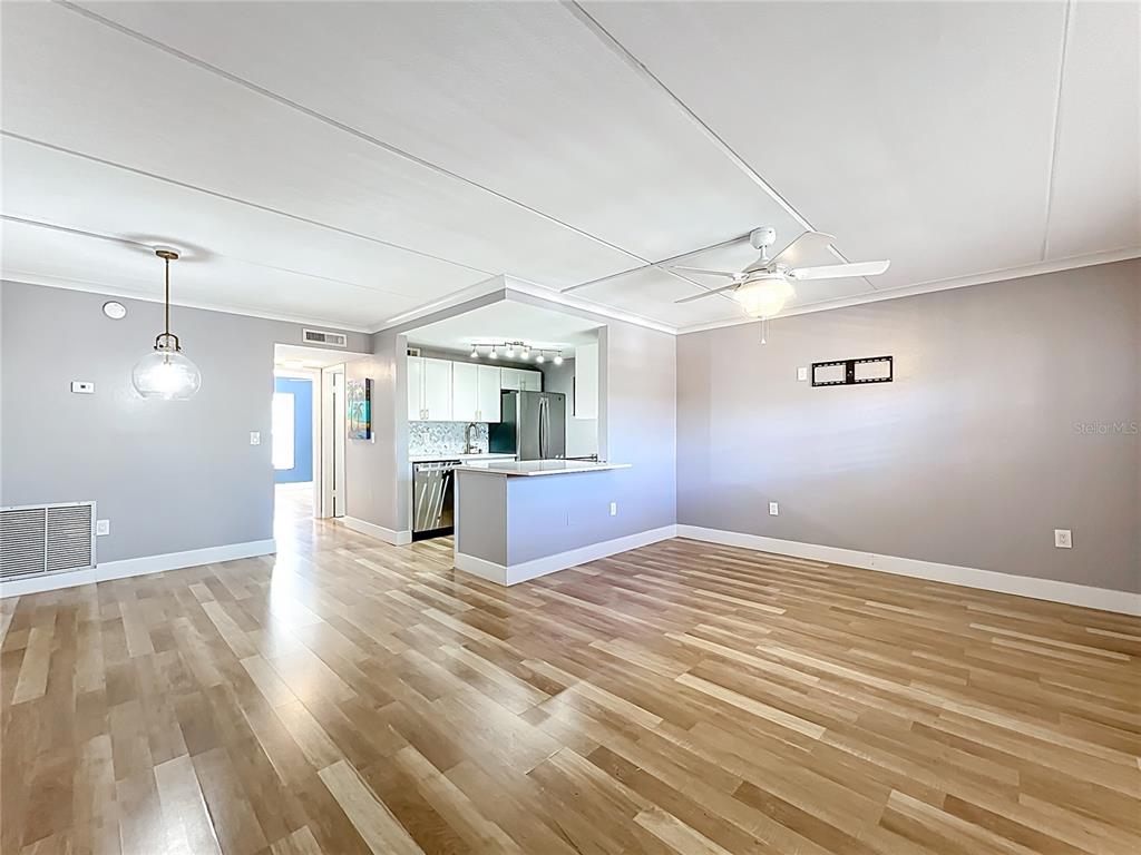 An open-concept living area features light wood flooring, gray walls, and an attached kitchen — 12760 INDIAN ROCKS ROAD UNIT 583, LARGO, FL