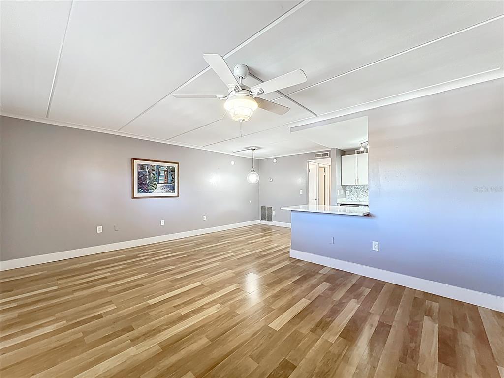 An open-concept living area features light gray walls, wood-look flooring, and a ceiling fan — 12760 INDIAN ROCKS ROAD UNIT 583, LARGO, FL