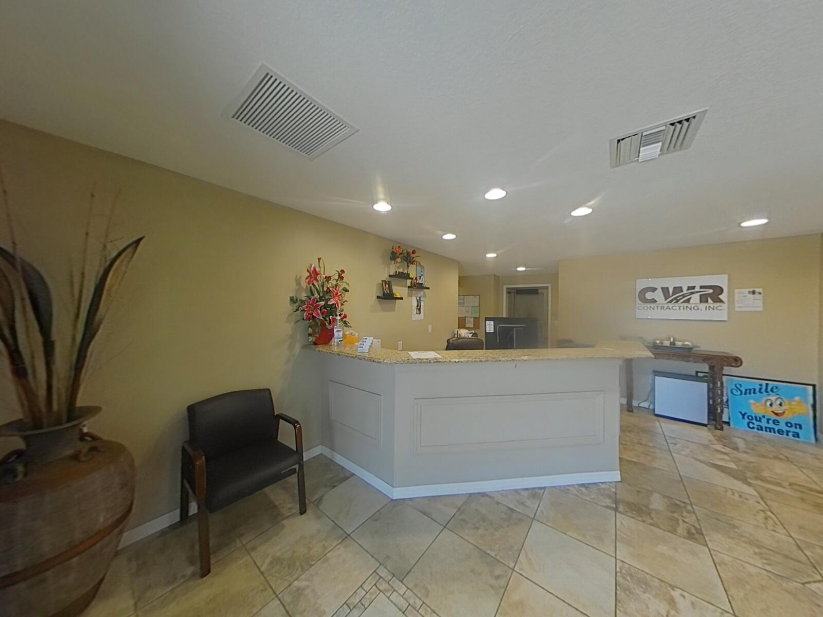 A reception area features a granite-topped desk, tile flooring, and a sign for CWR Contracting — 806 NW 9th Street, Okeechobee FL 34972, OKEECHOBEE, FL