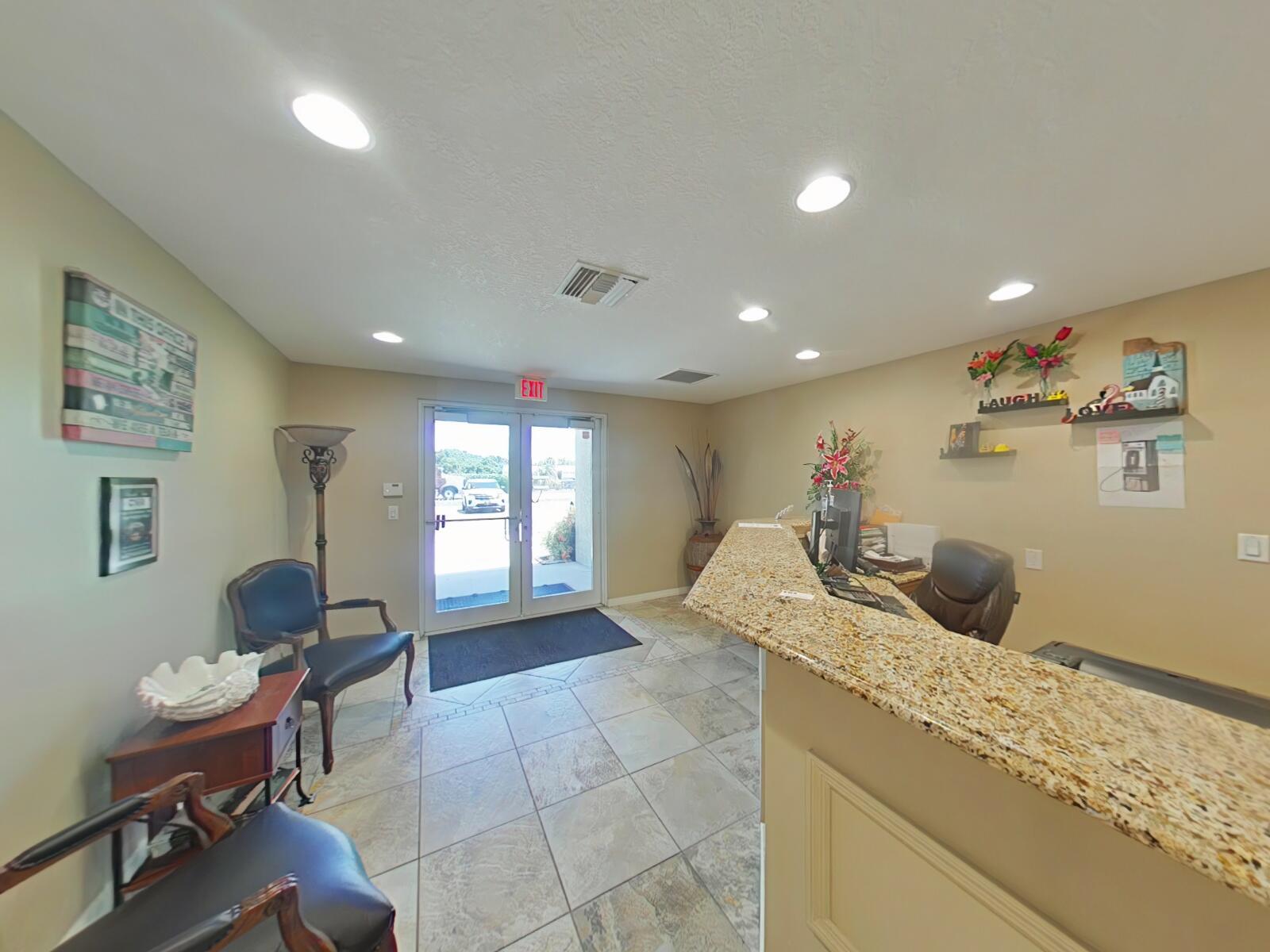 A reception area features a granite-topped desk, tile flooring, and a glass-paneled double door entrance — 806 NW 9th Street, Okeechobee FL 34972, OKEECHOBEE, FL