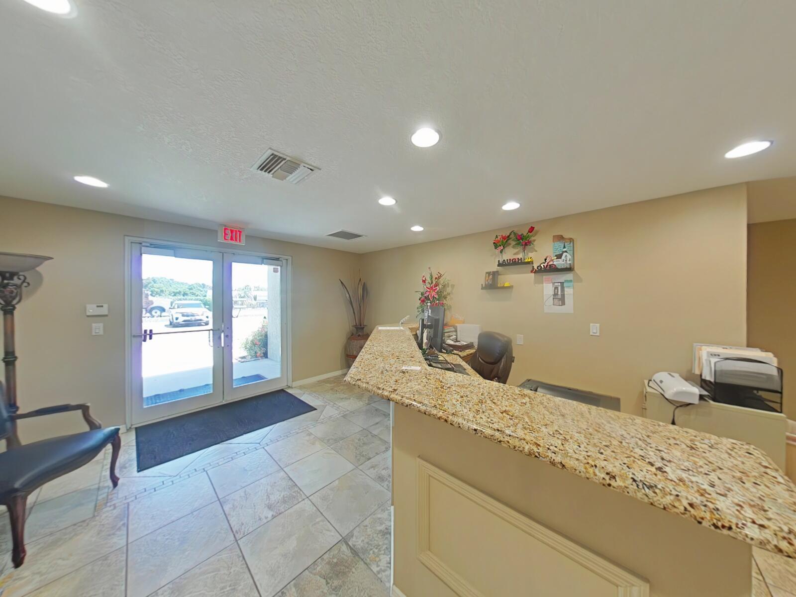 A reception area features a granite-topped desk, tile flooring, and a glass-paned double door entrance — 806 NW 9th Street, Okeechobee FL 34972, OKEECHOBEE, FL