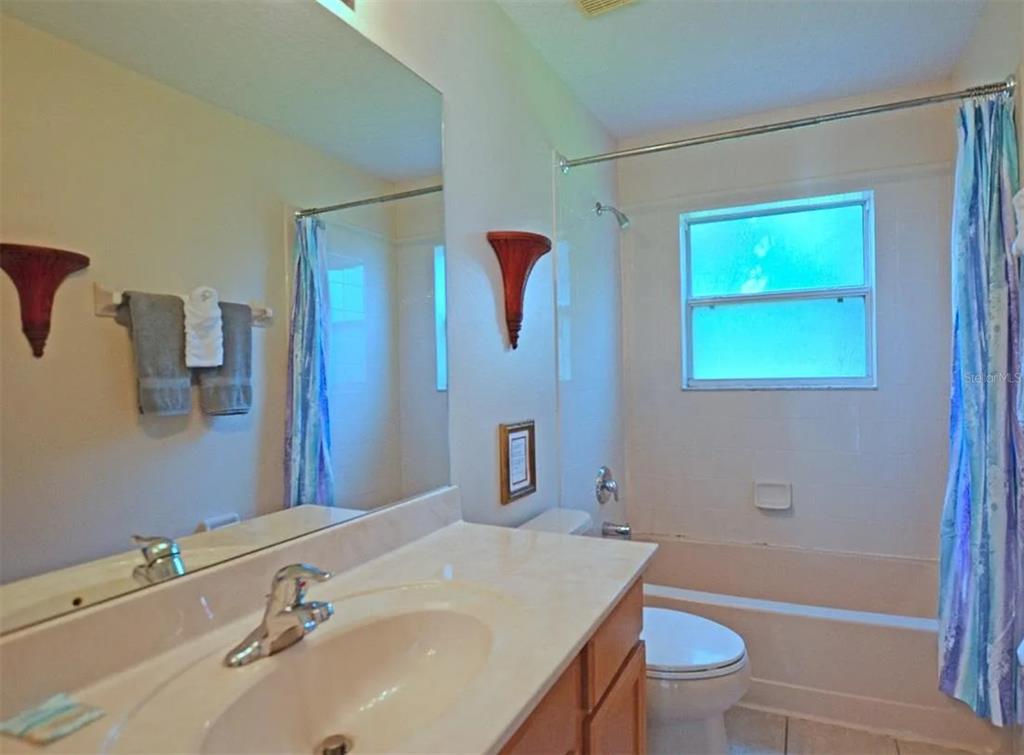 A bathroom features a vanity with a sink, a mirror, and a shower-tub combination — 8646 LA ISLA DRIVE, KISSIMMEE, FL