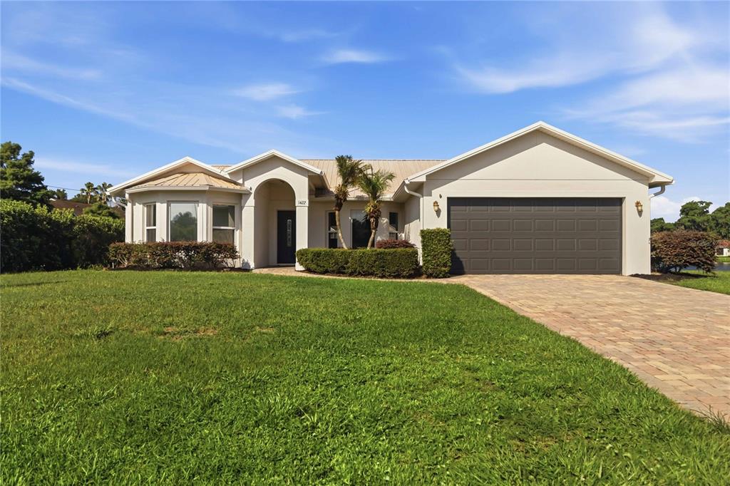 A single-story house with a beige exterior, a dark garage door, and a paved driveway — 1422 PATRICIA STREET, KISSIMMEE, FL