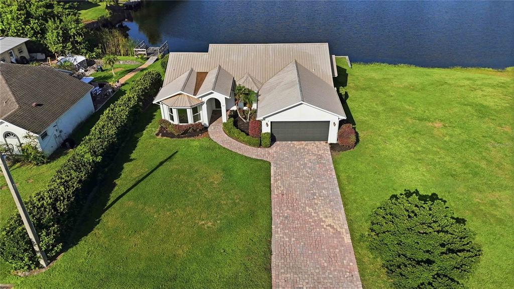 An aerial view shows a single-story house with a metal roof and brick paver driveway — 1422 PATRICIA STREET, KISSIMMEE, FL