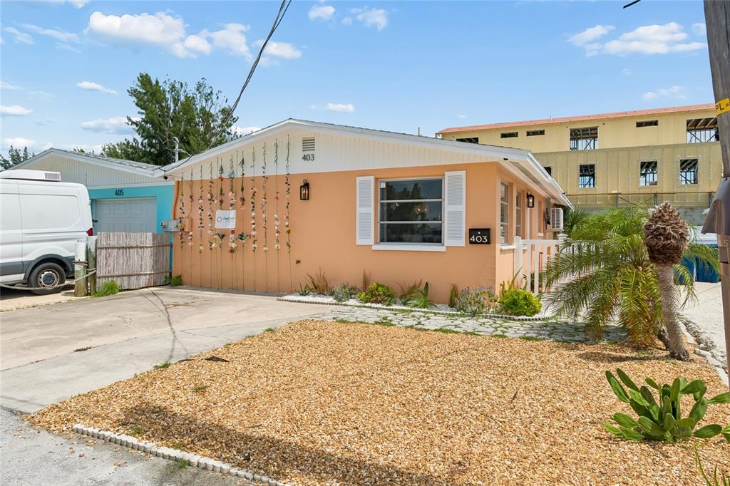 A peach-colored single-story house features a gravel front yard and a decorative floral wall hanging — 403 63RD STREET, HOLMES BEACH, FL