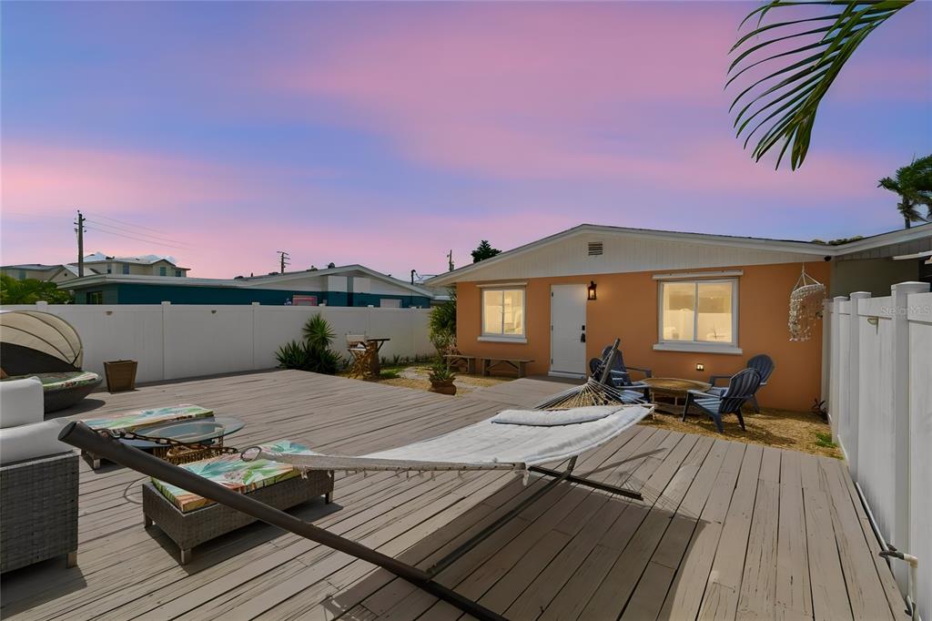 A wooden deck features a hammock, outdoor seating, and a white fence against a house — 403 63RD STREET, HOLMES BEACH, FL