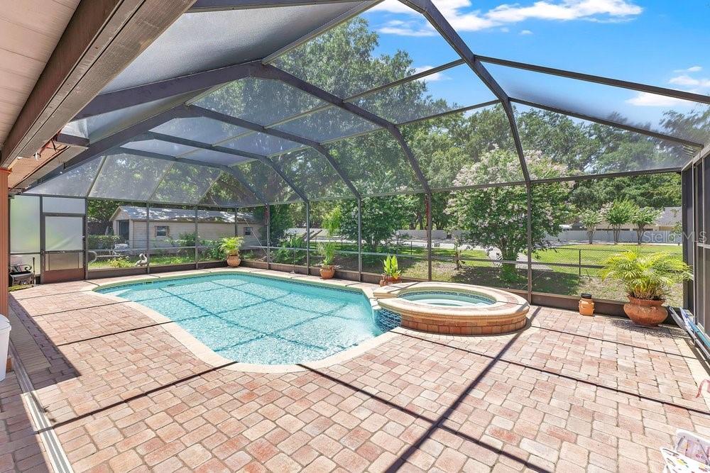 A screened-in patio features a swimming pool, a raised hot tub, and brick pavers — 1304 ARIANA WOODS CIRCLE, AUBURNDALE, FL