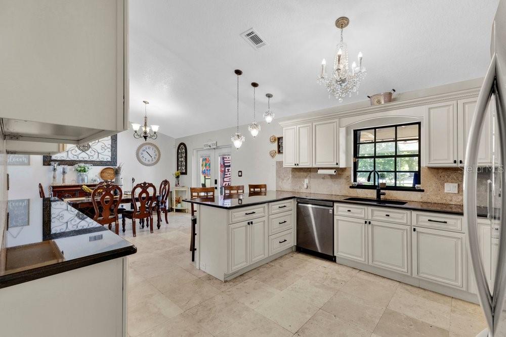 A kitchen with white cabinets, dark countertops, and a dining area with a chandelier — 1304 ARIANA WOODS CIRCLE, AUBURNDALE, FL
