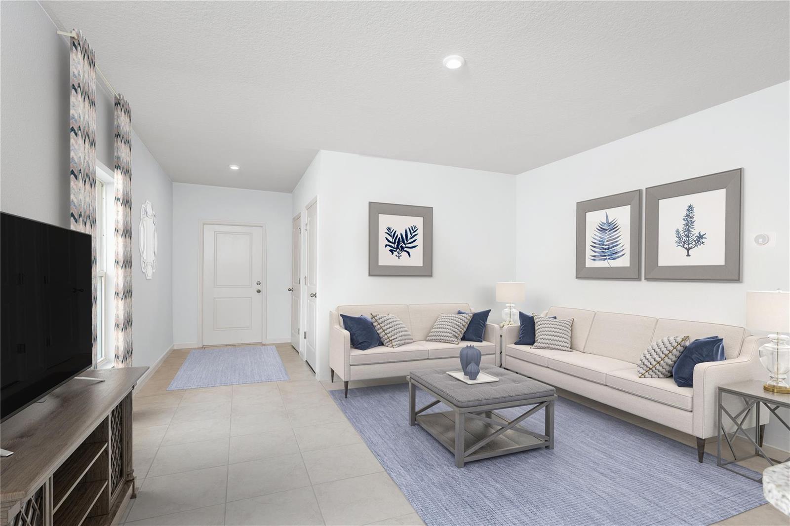 A living room features light tile floors, two beige sofas, a gray ottoman, and wall art — FL