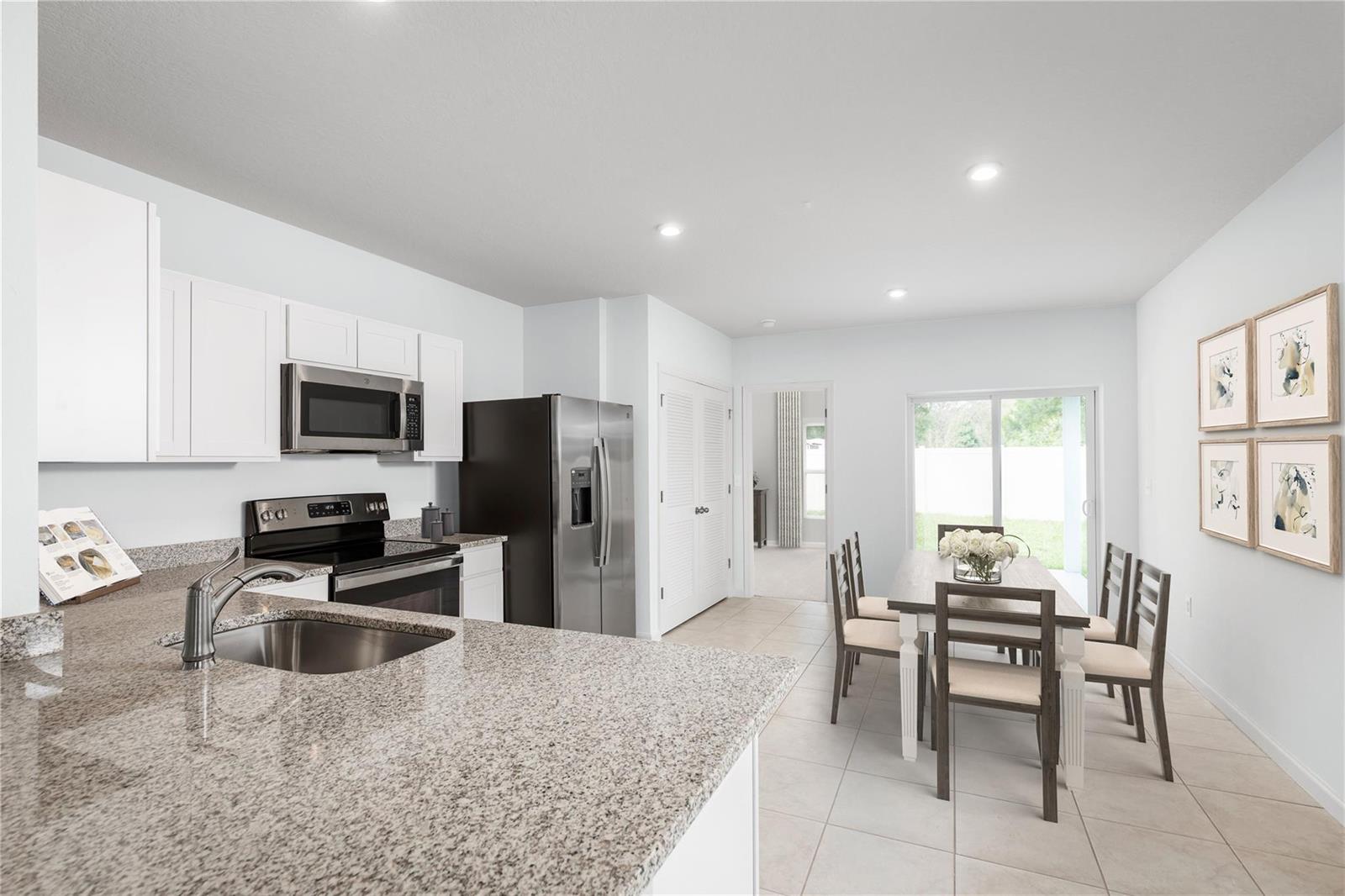 A kitchen with granite countertops and stainless steel appliances opens to a dining area — FL