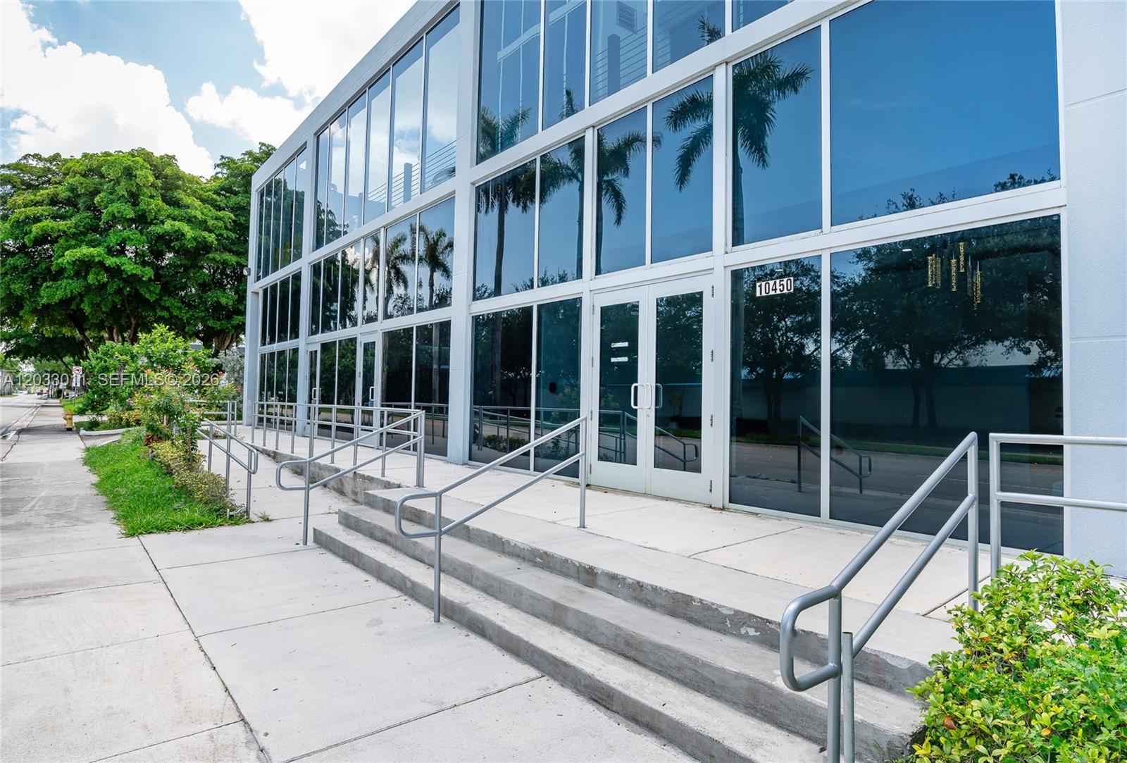 The exterior of a modern two-story office building features large glass windows and concrete stairs — 10450 NW 33rd St # 301, Doral FL 33172, DORAL, FL