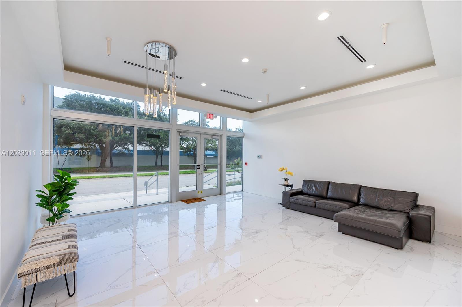 A modern lobby features white marble floors, a dark leather sectional, and floor-to-ceiling windows — 10450 NW 33rd St # 301, Doral FL 33172, DORAL, FL